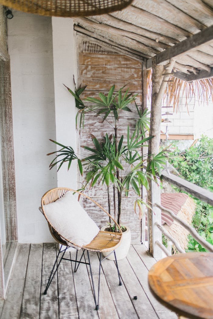 Wooden balcony with wicker armchair and potted plant on exotic resort in sunlight